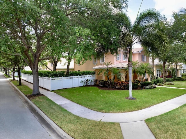 view of front of property with stucco siding, a tiled roof, fence, and a front lawn