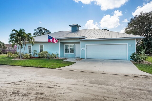 4732 SE Starling Cir, Stuart, FL 34997 - view of front facade featuring a front yard, concrete driveway, metal roof, and a garage