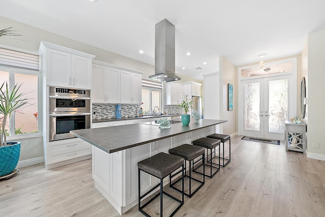 kitchen featuring french doors, dark countertops, island range hood, and tasteful backsplash