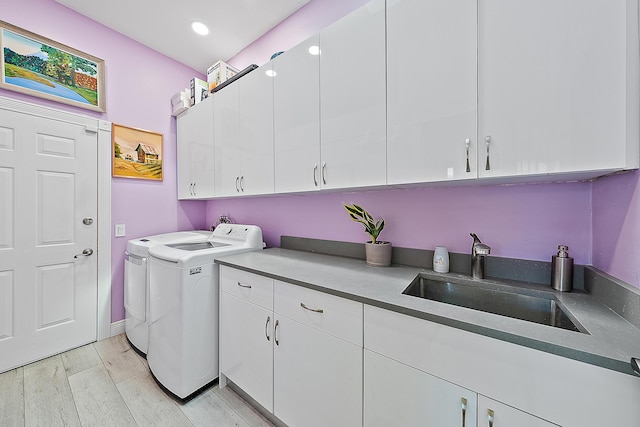 laundry room with recessed lighting, light wood-style flooring, washing machine and clothes dryer, a sink, and cabinet space
