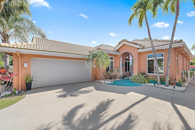 view of front of property with a garage, stucco siding, concrete driveway, and a tile roof