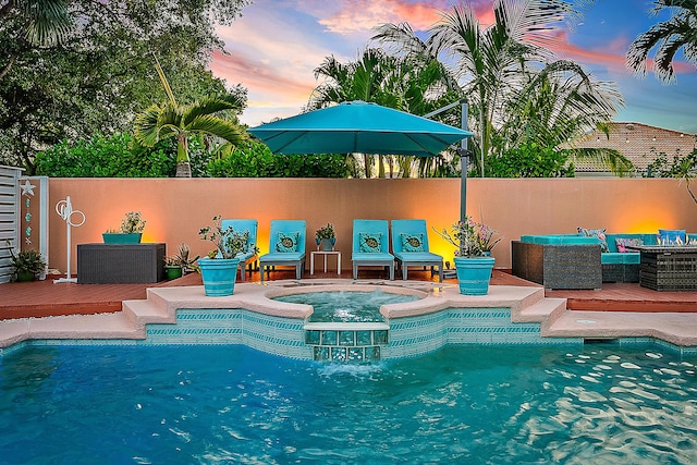 pool at dusk featuring a fenced in pool, a wooden deck, and an in ground hot tub