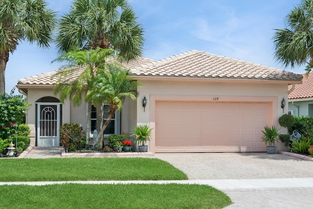 mediterranean / spanish home with stucco siding, a tiled roof, a garage, driveway, and a front yard