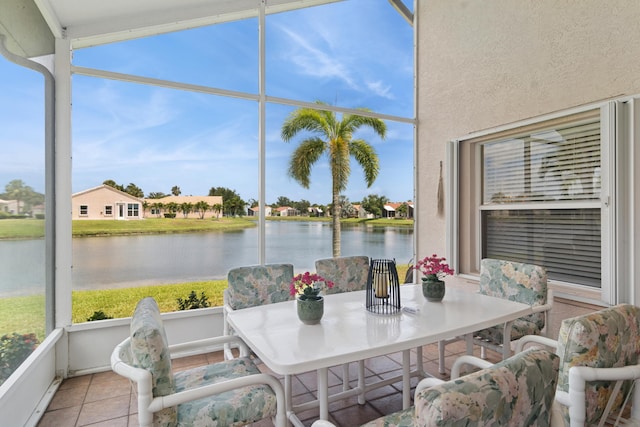 sunroom / solarium with tile patterned floors and a water view