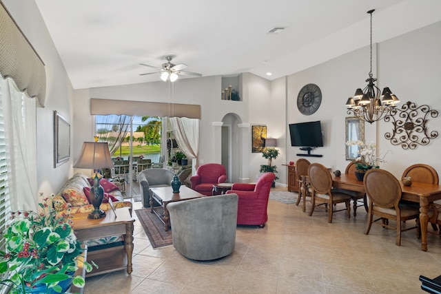 living area featuring arched walkways, light tile patterned floors, ceiling fan with notable chandelier, visible vents, and high vaulted ceiling
