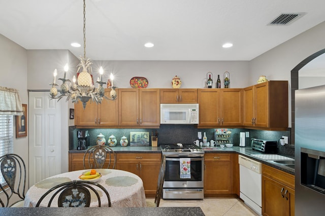 kitchen featuring visible vents, dark countertops, appliances with stainless steel finishes, and brown cabinetry