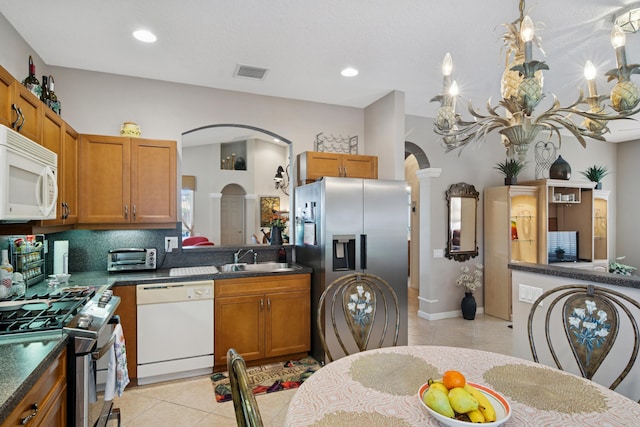 kitchen featuring a sink, light tile patterned flooring, visible vents, arched walkways, and appliances with stainless steel finishes