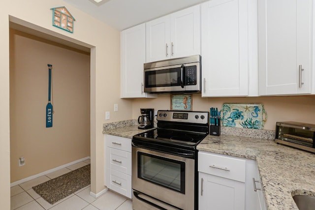 13 Lake Vista Trl Unit 202, Port Saint Lucie, FL 34952 - kitchen featuring appliances with stainless steel finishes, light tile patterned flooring, light stone countertops, and white cabinets