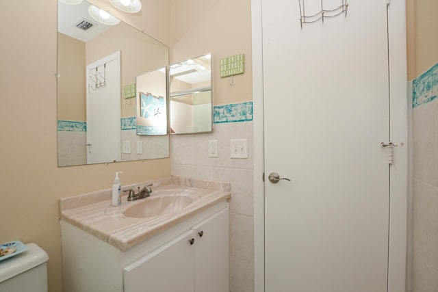 13 Lake Vista Trl Unit 202, Port Saint Lucie, FL 34952 - half bathroom featuring tile walls, visible vents, toilet, and vanity