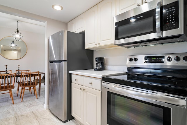 kitchen featuring marble finish floor, light countertops, white cabinets, appliances with stainless steel finishes, and decorative light fixtures