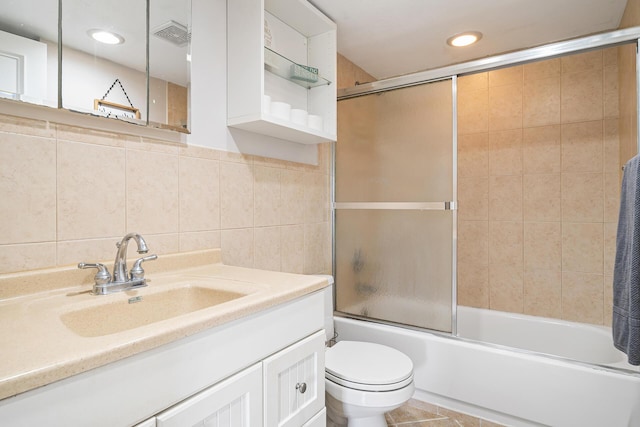 full bathroom with visible vents, vanity, toilet, tile walls, and enclosed tub / shower combo