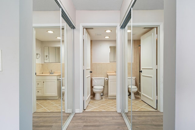 full bath featuring vanity, wood finished floors, toilet, and tile walls