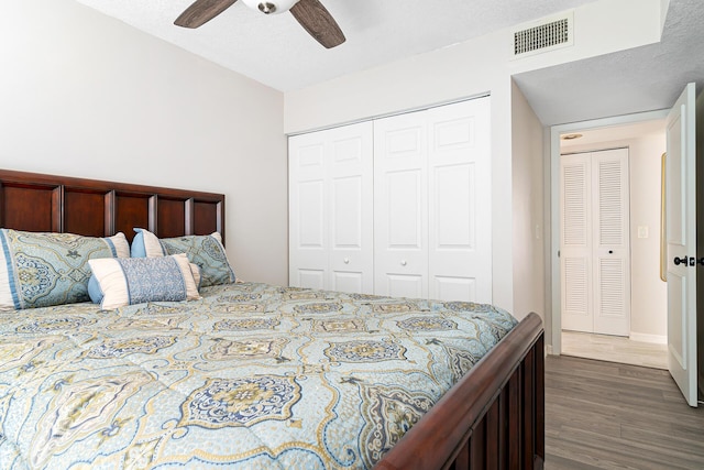 bedroom with visible vents, a closet, baseboards, dark wood-type flooring, and a ceiling fan