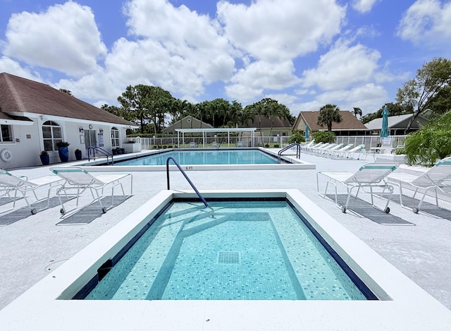 pool with fence, a community hot tub, and a patio area