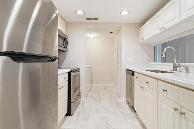 kitchen with washer and dryer, appliances with stainless steel finishes, a sink, light countertops, and visible vents