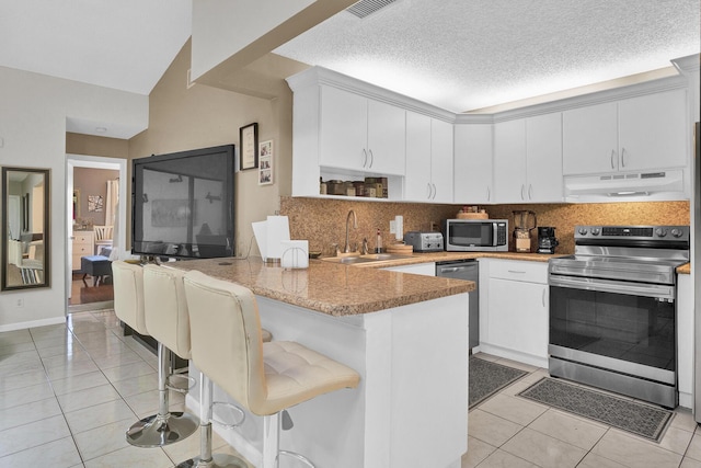 136 Centennial Ct, Deerfield Beach, FL 33442 - kitchen with under cabinet range hood, stainless steel appliances, light tile patterned floors, a sink, and a peninsula