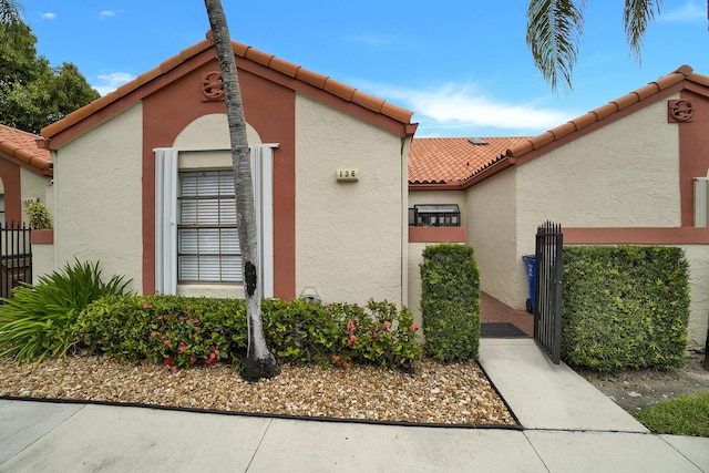 136 Centennial Ct, Deerfield Beach, FL 33442 - view of property exterior featuring fence, a tiled roof, a gate, and stucco siding