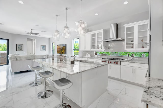 7015 NW 27th Ave, Boca Raton, FL 33496 - kitchen featuring recessed lighting, stainless steel gas stovetop, wall chimney range hood, marble finish floor, and a sink