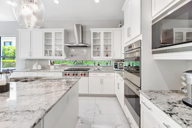 7015 NW 27th Ave, Boca Raton, FL 33496 - kitchen featuring wall chimney range hood, white cabinets, marble finish floor, and appliances with stainless steel finishes