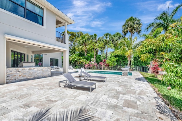 7015 NW 27th Ave, Boca Raton, FL 33496 - view of patio featuring an outdoor kitchen, fence, ceiling fan, a fenced in pool, and a balcony