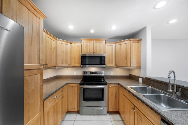 kitchen featuring recessed lighting, a sink, stainless steel appliances, light tile patterned floors, and dark countertops