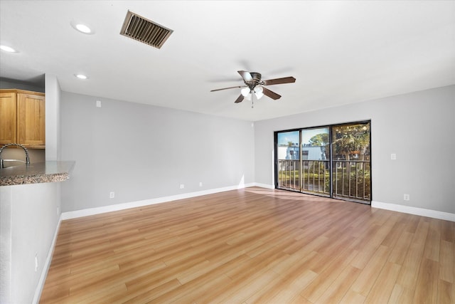 unfurnished living room with visible vents, ceiling fan, light wood finished floors, and a sink