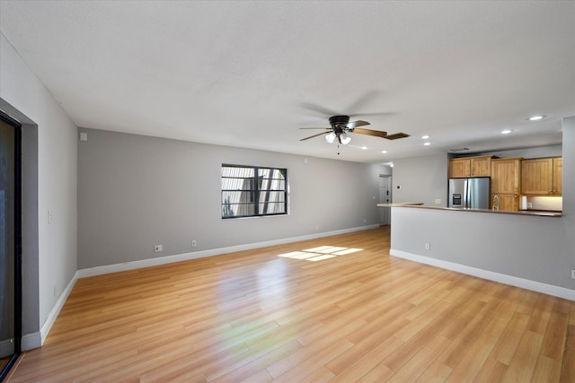 unfurnished living room featuring a sink, baseboards, recessed lighting, light wood finished floors, and a ceiling fan