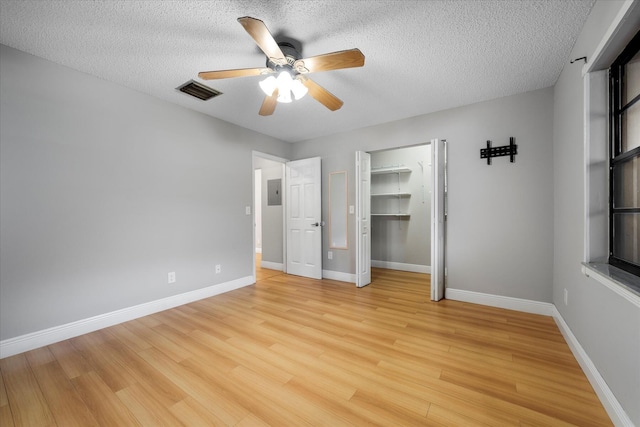 unfurnished bedroom featuring baseboards, visible vents, a textured ceiling, and light wood finished floors