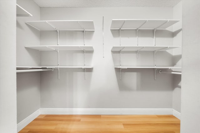 walk in closet with wood finished floors