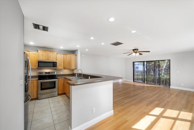 kitchen featuring a sink, appliances with stainless steel finishes, visible vents, open floor plan, and a peninsula