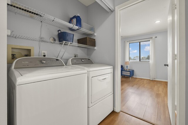 laundry area featuring washing machine and dryer, baseboards, light wood-style floors, and laundry area