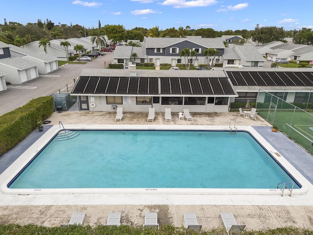 community pool with fence, a patio area, and a residential view