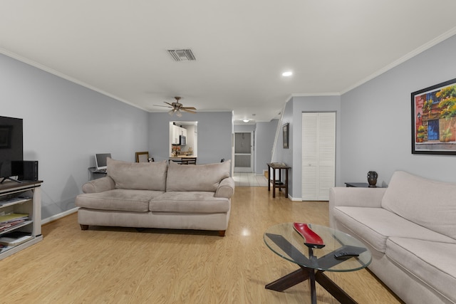 living room featuring baseboards, ornamental molding, light wood-style floors, and visible vents