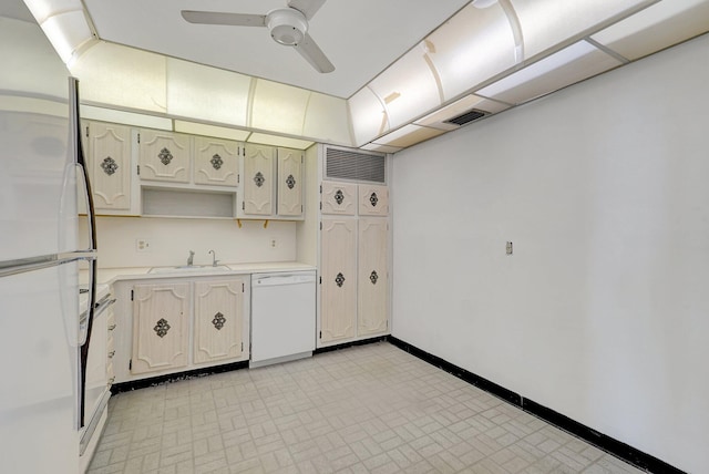 kitchen featuring a sink, ceiling fan, light countertops, baseboards, and white appliances