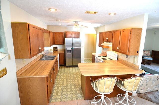 kitchen featuring under cabinet range hood, a sink, white electric range oven, a peninsula, and stainless steel refrigerator with ice dispenser