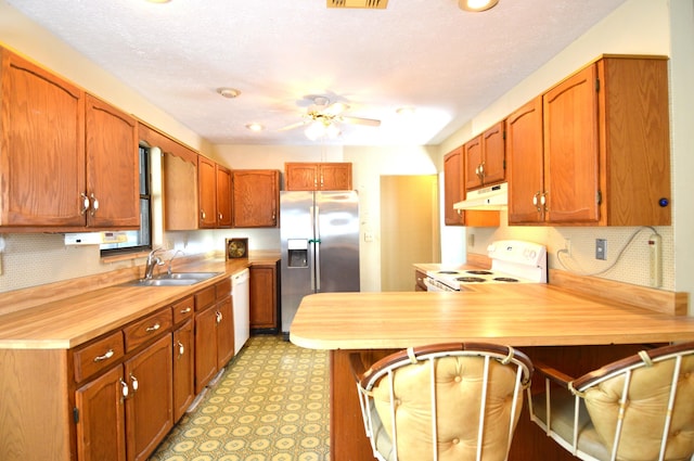kitchen featuring under cabinet range hood, a sink, white appliances, a peninsula, and ceiling fan
