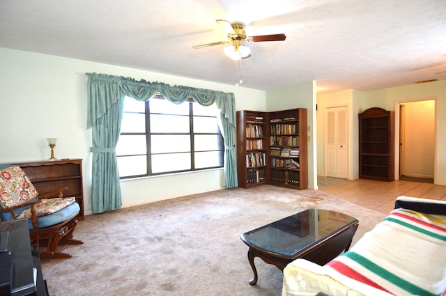 living area featuring ceiling fan, baseboards, a textured ceiling, and carpet