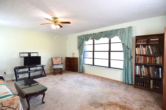 living area with carpet, a textured ceiling, baseboards, and ceiling fan