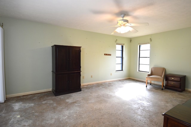 interior space featuring unfinished concrete flooring, baseboards, and a ceiling fan