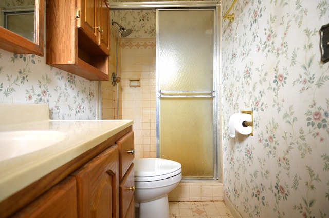 bathroom featuring a shower stall, toilet, vanity, and wallpapered walls