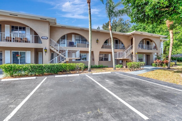 view of property featuring uncovered parking and stairway