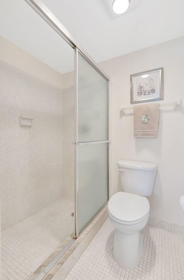 bathroom with baseboards, a stall shower, tile patterned floors, and toilet