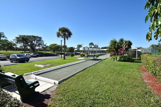 view of community with a lawn and uncovered parking