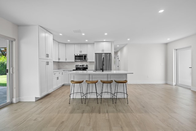 1269 NW 4th St, Boca Raton, FL 33486 - kitchen with stainless steel appliances, a kitchen island, white cabinets, a kitchen bar, and light wood finished floors