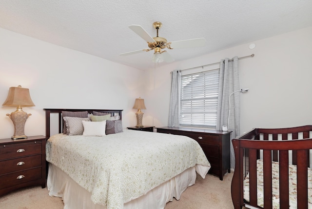 bedroom with a ceiling fan, a textured ceiling, and light carpet