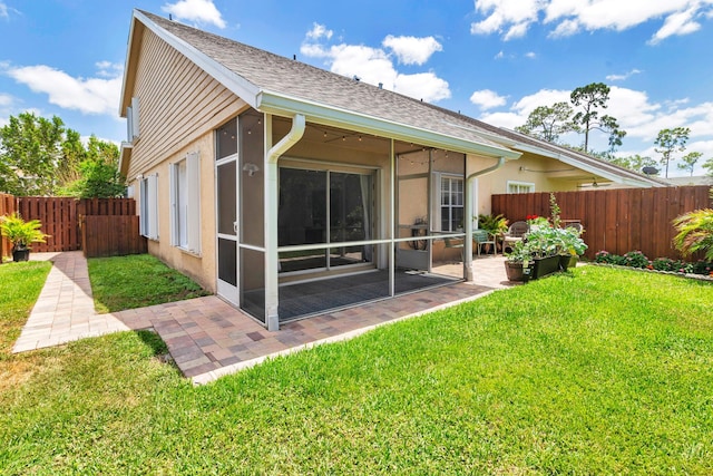 back of house with roof with shingles, a sunroom, a fenced backyard, a patio area, and a lawn