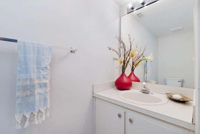 bathroom with toilet, visible vents, and vanity