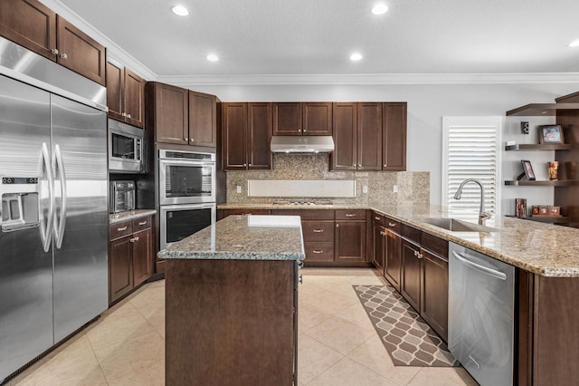 kitchen featuring a kitchen island, crown molding, a sink, built in appliances, and under cabinet range hood