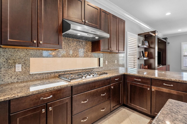 kitchen featuring ornamental molding, dark brown cabinets, under cabinet range hood, tasteful backsplash, and stainless steel gas stovetop