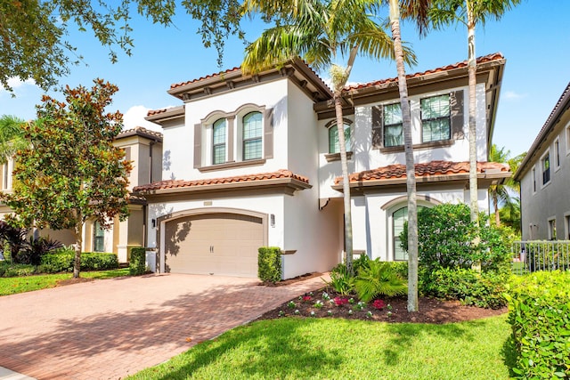 mediterranean / spanish home featuring a tiled roof, decorative driveway, and stucco siding